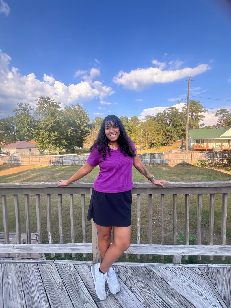 Hallie smiling on a wooden deck under a blue sky